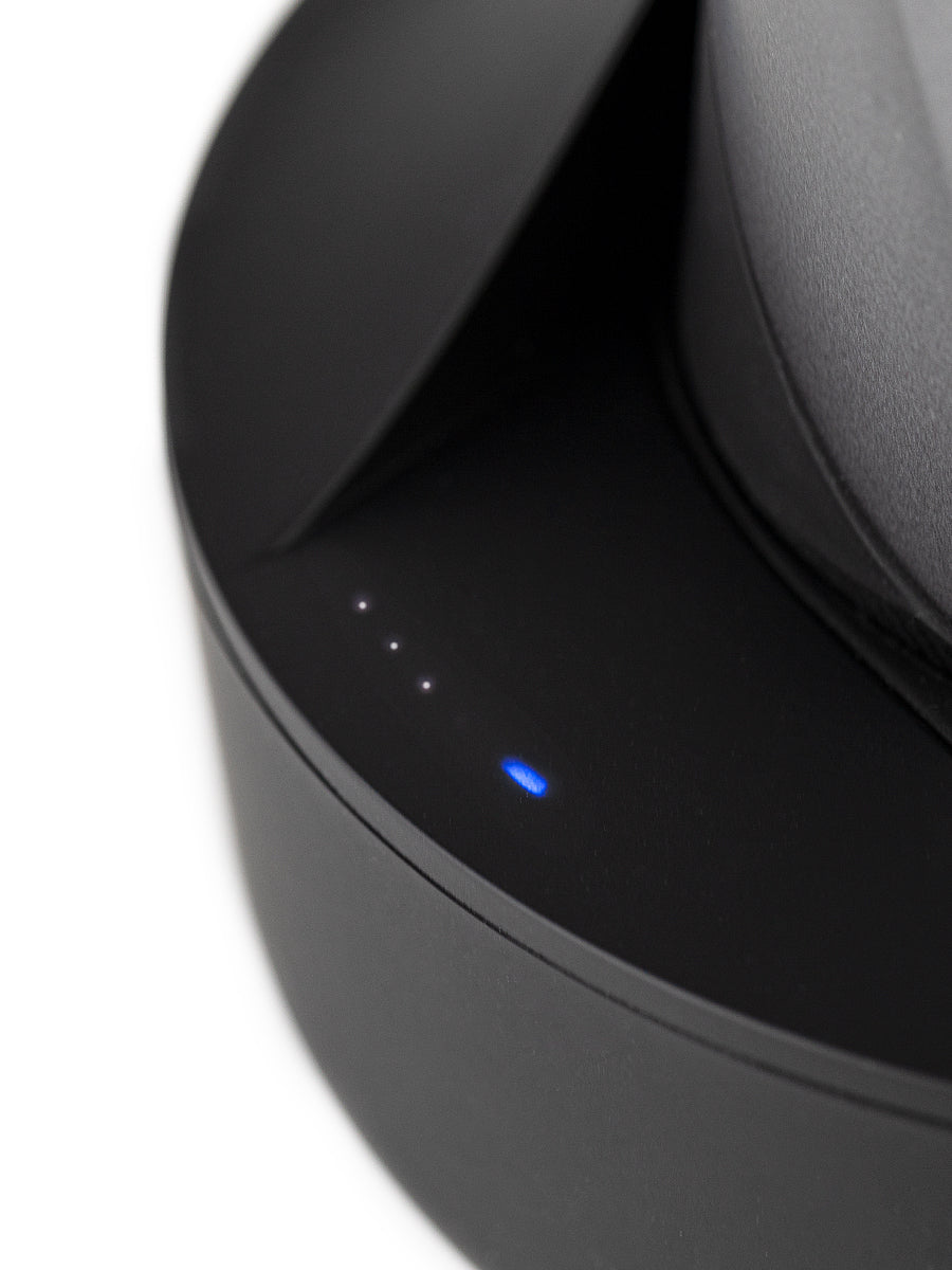 Close up shot of four small blue and white lights on black Puffco wireless charger